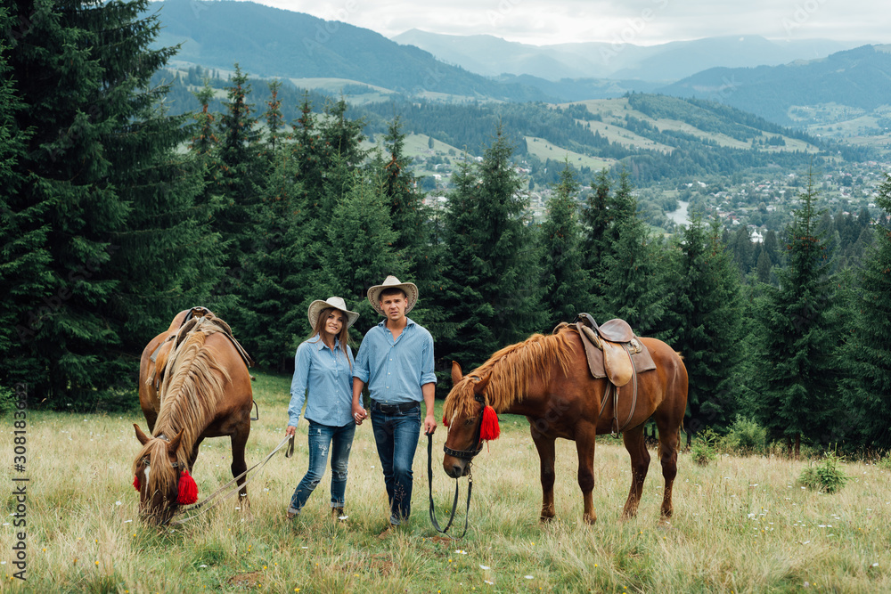 young beautiful couple walk with horses in mountains young beautiful couple walk with horses in mountains