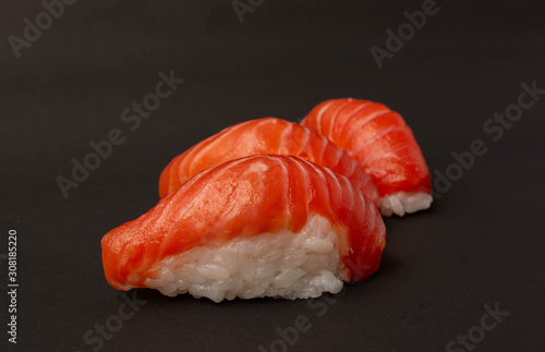 Salmon sushi on black background.