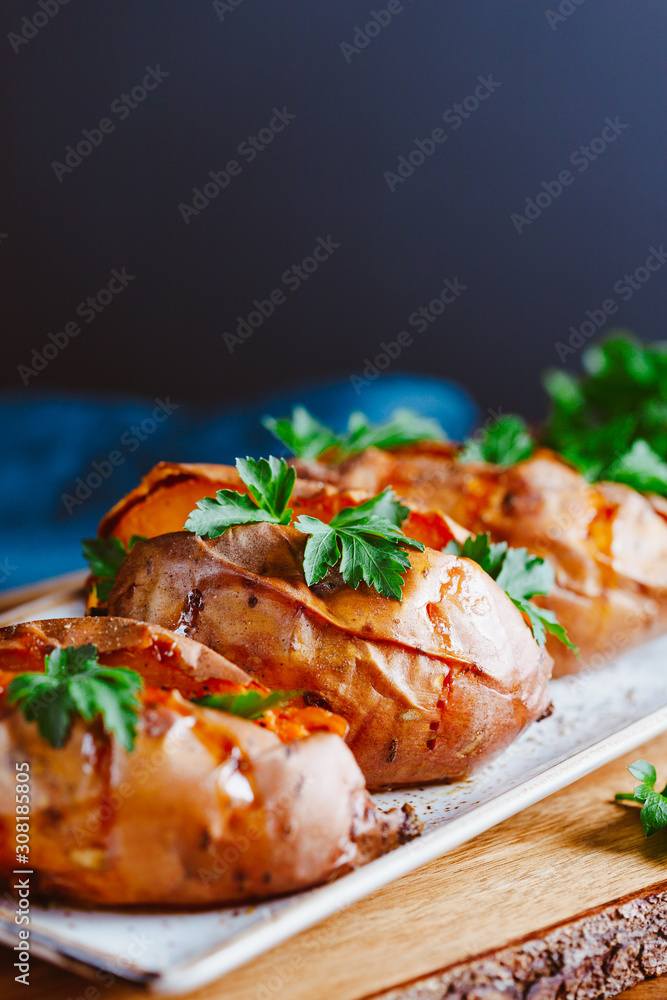 Baked three sweet potatoes with fresh parsley on a white ceramic dish. Healthy veggie dinner or lunch. Baked three sweet potatoes with fresh parsley on a white ceramic dish. Healthy veggie dinner or lunch.
