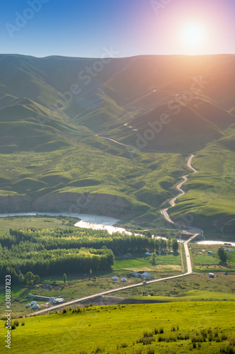 Alpine meadow with winding road in mountain ranges