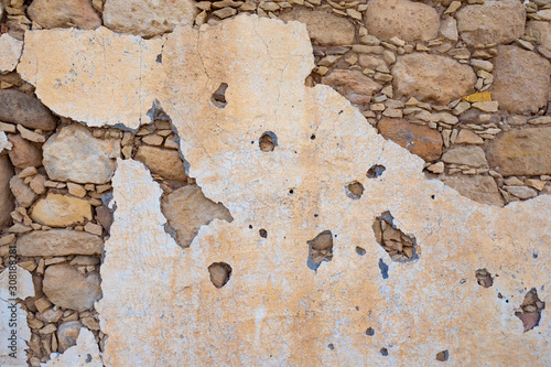 Texture of the stone. Background - a wall of solid stone. Old stucco. Stone wall. Paint drops off the wall. Background from the building. Decrepit side. Construction of the last century.