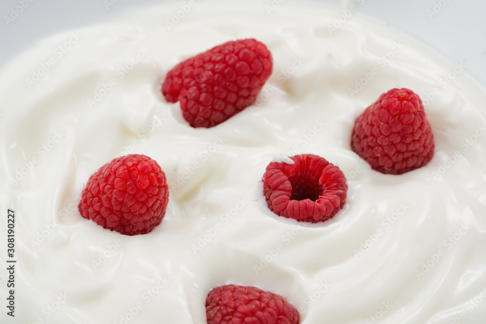 Closeup of fresh raspberries in white yogurt Closeup of fresh raspberries in white yogurt