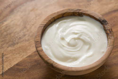 organic white yogurt in olive wood bowl on table