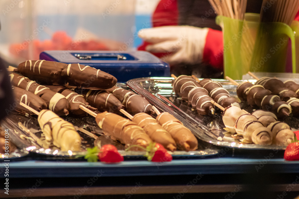 Obst mit Schokolade überzogen als Schokoglasur oder kandiertes Obst ist eine weihnachtliche Leckerei am Marktstand auf dem Weihnachtsmarkt oder der Kirmes und lockt Naschkatzen und Leckermäuler