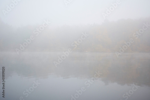 Landscape of an early morning lake and a boat with a fisherman