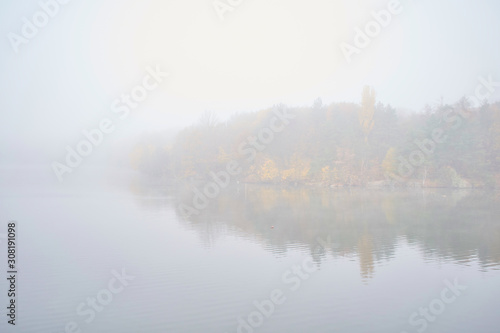 Landscape of an early morning lake and a boat with a fisherman