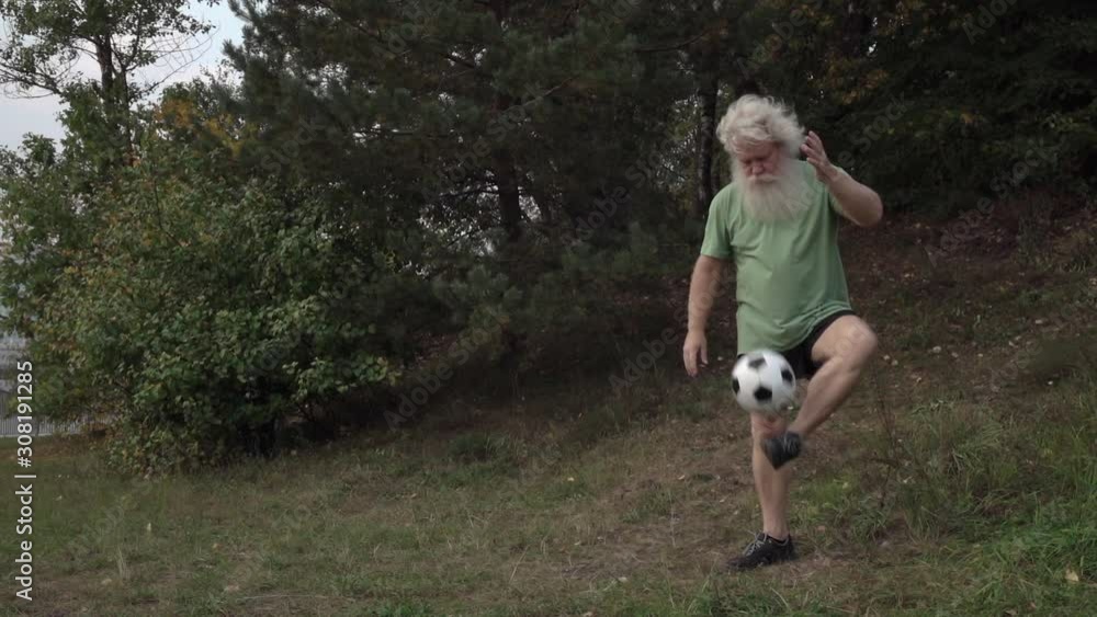Sportive senior Caucasian man with splendid grey hair, moustache and beard is juggling soccer ball on park background. Beautiful portrait of active European handsome people in summer leisure. Sportive senior Caucasian man with splendid grey hair, moustache and beard is juggling soccer ball on park background. Beautiful portrait of active European handsome people in summer leisure.