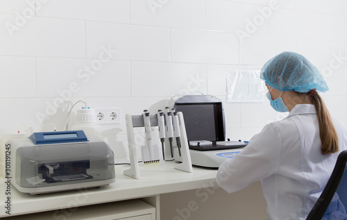 Female lab assistant looking at modern machine for analisis