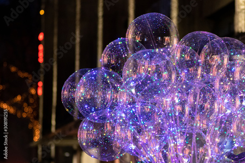 Leuchtende bunte transparente funkelnde Luftballons auf einem Weihnachtsmarkt oder einer Kirmes leuchten in der Dunkelheit und lassen Kinderaugen strahlen photo