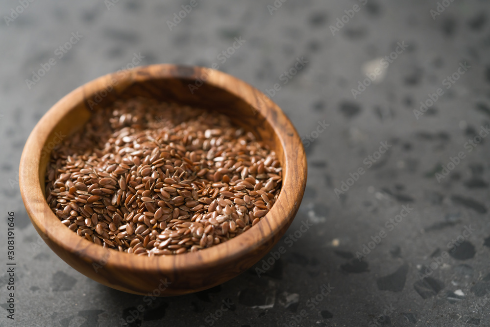 Flax seeds in olive wood bowl on terrazzo surface with copy space Flax seeds in olive wood bowl on terrazzo surface with copy space