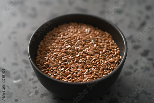 Flax seeds in black bowl on terrazzo surface with closeup