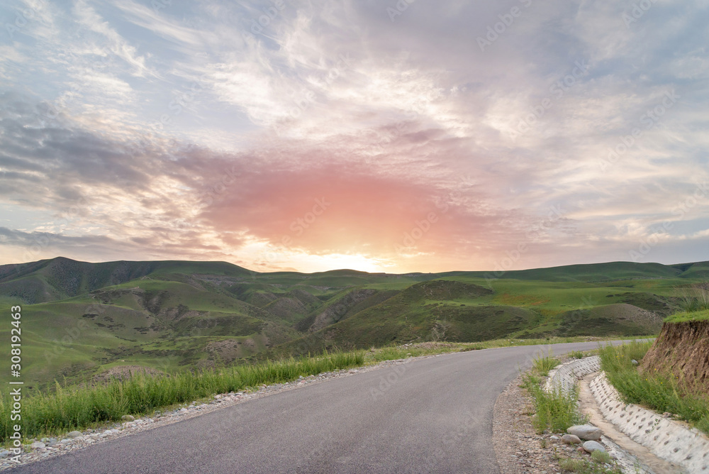 Empty rural road in mountains with morning sunrise sky