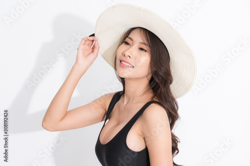 Beautiful asian girl wearing black swimming suit dress, wearing a white hat in a standing position looked up at the top in a summer fashion on isolated white background.
