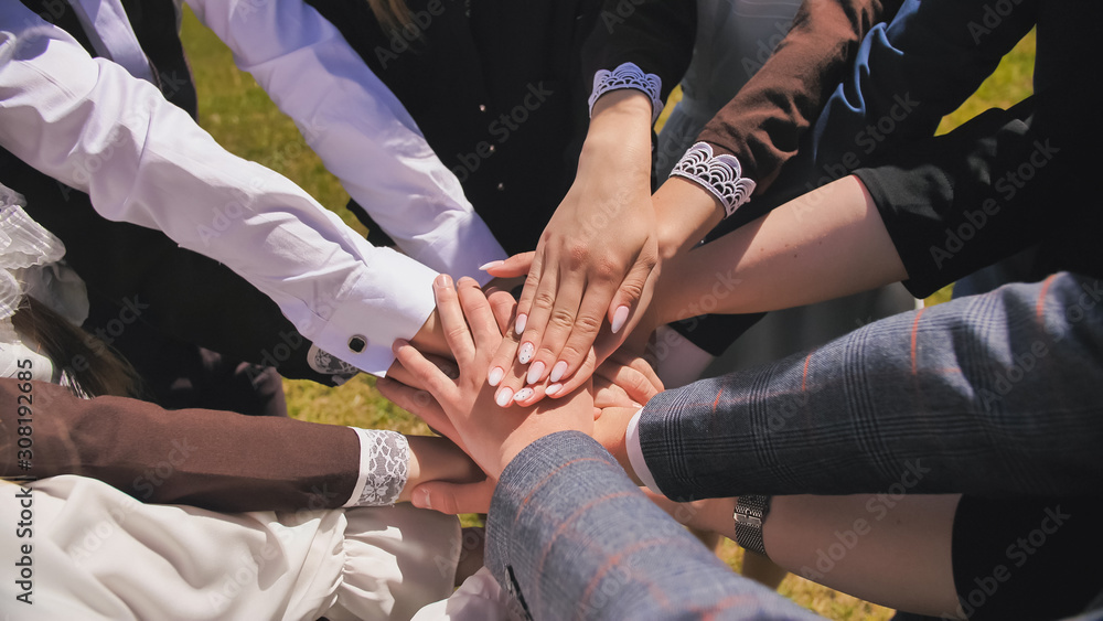 Happy friends graduates join hands together. The concept of a friendly team. Happy friends graduates join hands together. The concept of a friendly team.