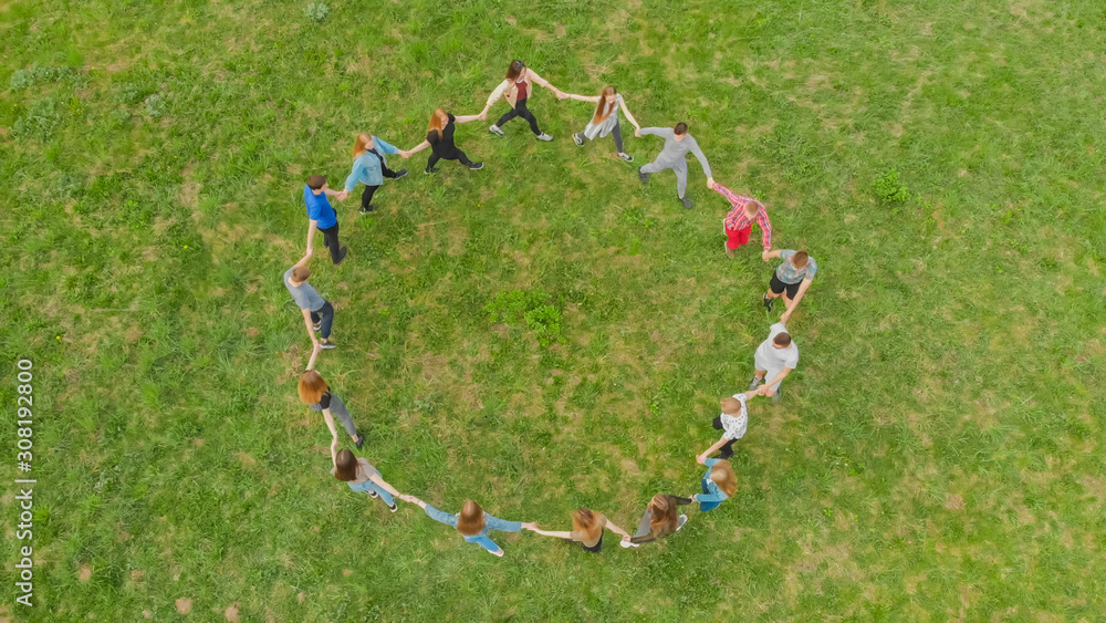 Friends in a circle holding hands make a round dance in the field. - obrazy, fototapety, plakaty 