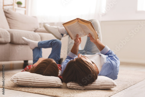 Little girl and father enjoying book together, laying on floor photo