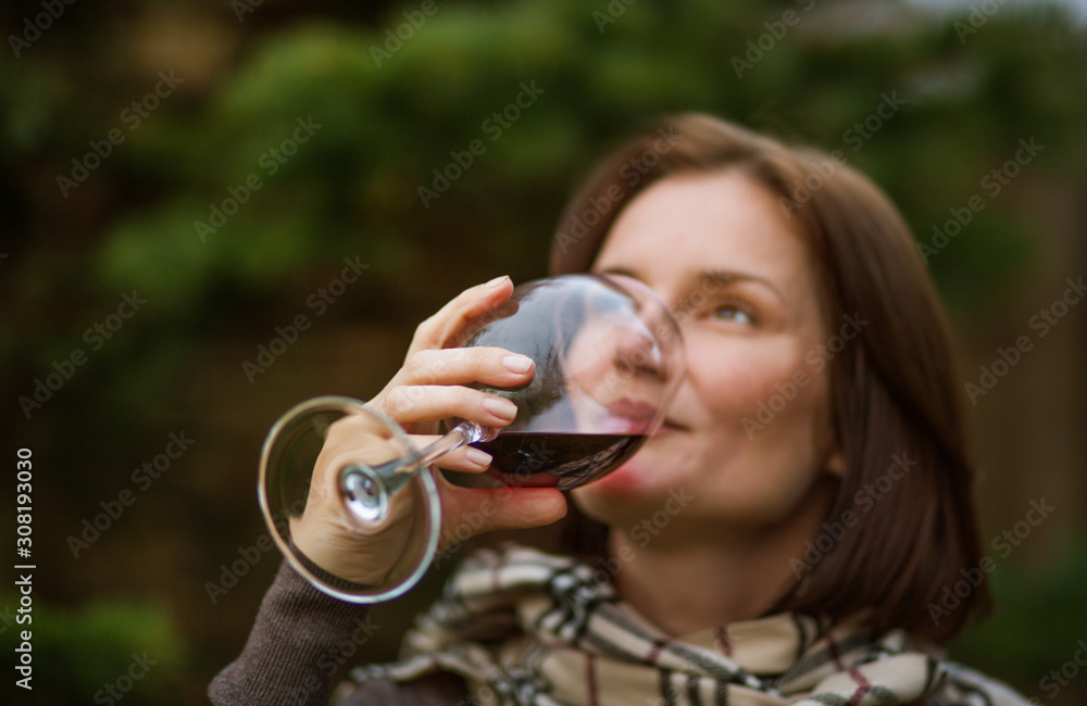 beautiful girl drinks red young wine from a glass