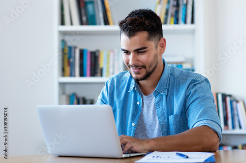 Handsome mexican hipster man sending email with laptop
