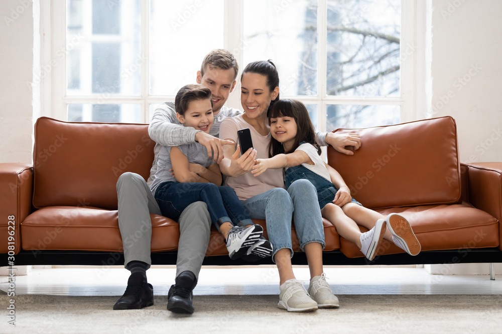 Happy family with two children having good time using smartphone. Happy family with two children having good time using smartphone.