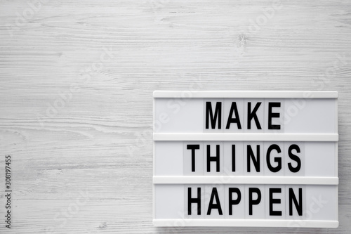 'Make things happen' words on a modern board on a white wooden surface, top view. Overhead, from above, flat lay. Space for text.