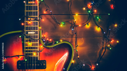 Old, jazz electric guitar with a luminous garland. New Year greeting card for musician, guitarist.