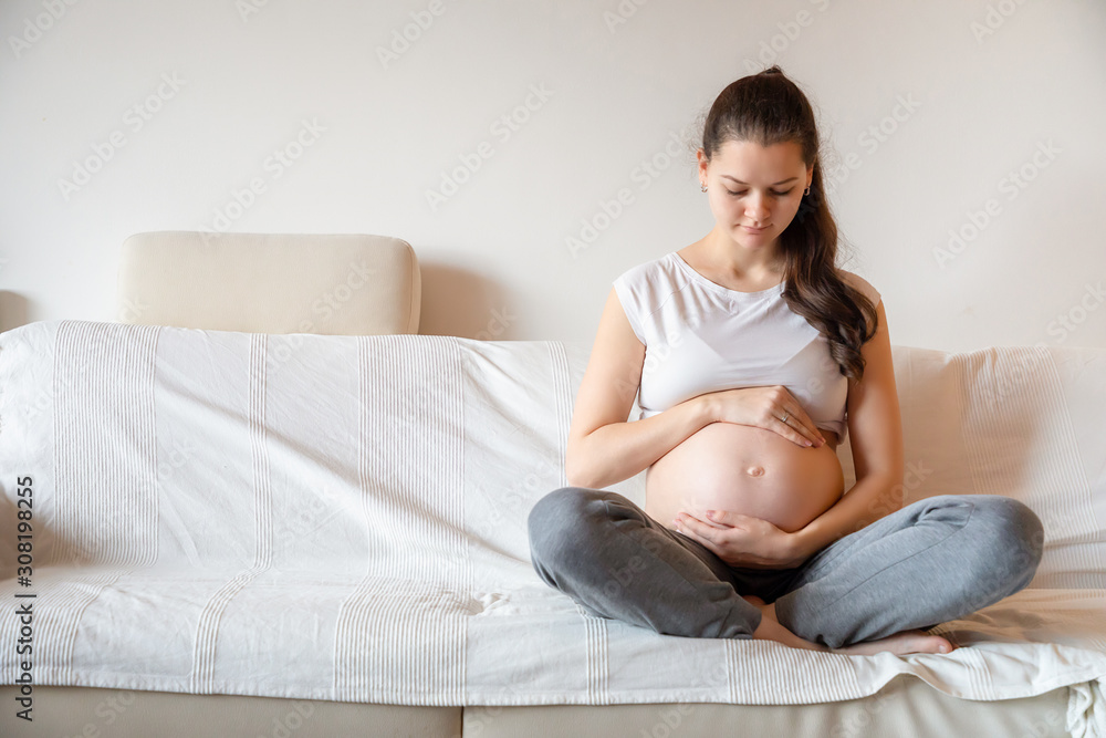 Young pregnant woman sitting on sofa Young pregnant woman sitting on sofa