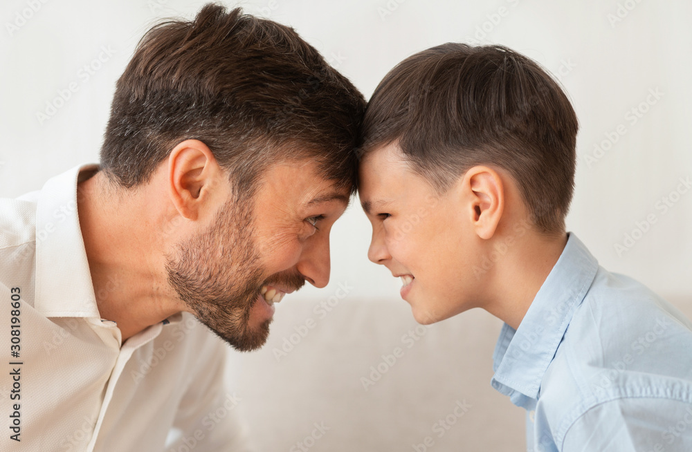 Happy Father And Son Bowing Heads Touching Foreheads, White Background Happy Father And Son Bowing Heads Touching Foreheads, White Background