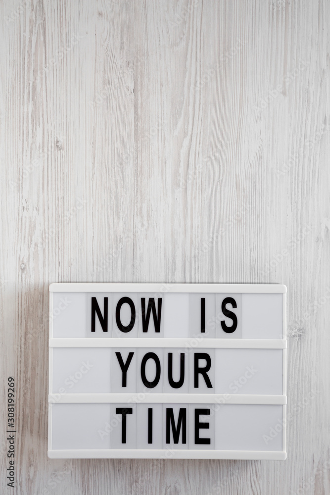 'Now is your time' words on a lightbox on a white wooden surface, top view. Overhead, from above, flat lay. Copy space. 'Now is your time' words on a lightbox on a white wooden surface, top view. Overhead, from above, flat lay. Copy space.