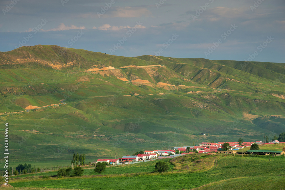 Pastoral village with red roof farmhouses beside a mountain in valley