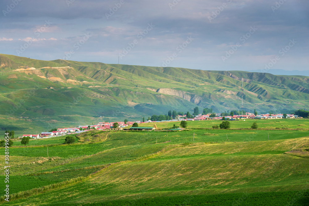 Pastoral village in valley with farm field on foreground