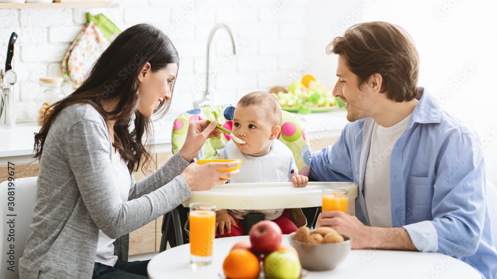 Happy parents feeding baby son with healthy porridge Happy parents feeding baby son with healthy porridge