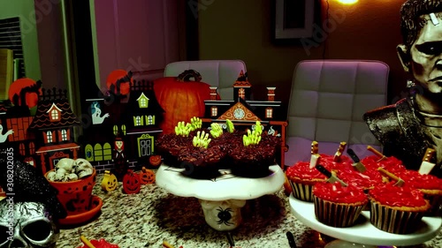 Spooky halloween cupcakes with hands hatchets and knives in them  with a skull and small town background photo