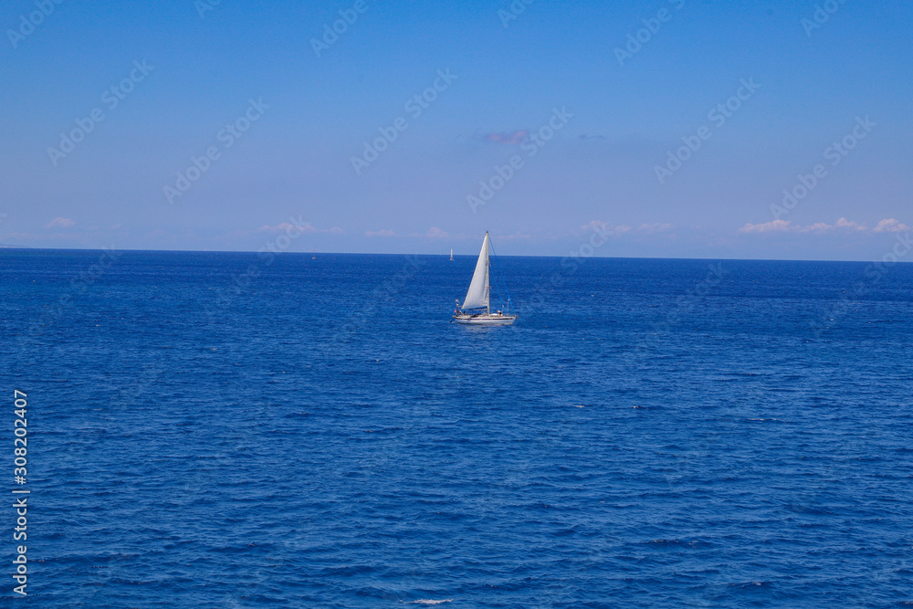 Small sailboat in the blue ocean water.