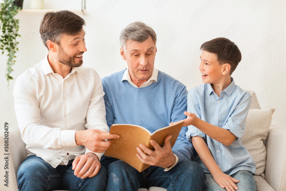 Grandfather Reading Book With Mature Son And Grandson At Home Grandfather Reading Book With Mature Son And Grandson At Home