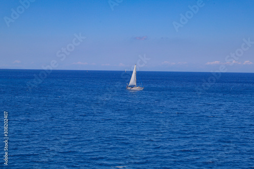 Small sailboat in the blue ocean water. © MagioreStockStudio