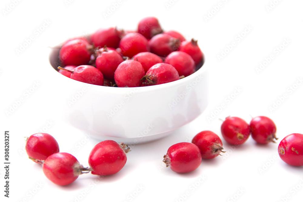 Berries Crataegus Oxyacantha, which is also known as Hawthorn. Berries are in the white cup, isolated over white background. Health concept. Herbal medicine. Selective focus Berries Crataegus Oxyacantha, which is also known as Hawthorn. Berries are in the white cup, isolated over white background. Health concept. Herbal medicine. Selective focus