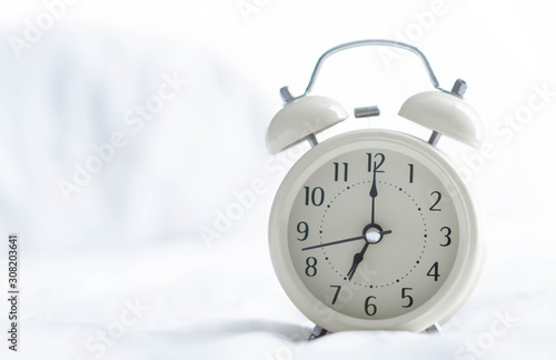 Alarm clock on wooden table for wake up time with light from window, selective focus