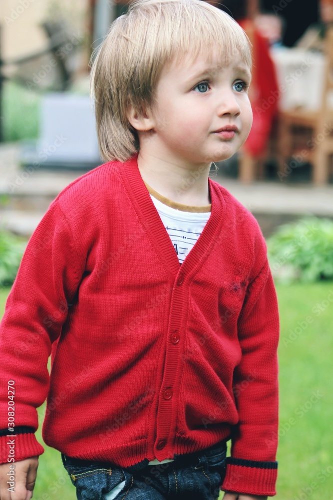 Portrait of little caucasian boy in casual clothes in home garden