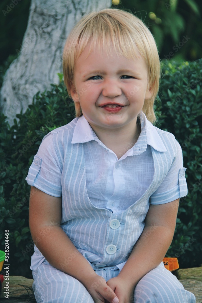 Portrait of little caucasian boy in casual clothes in home garden