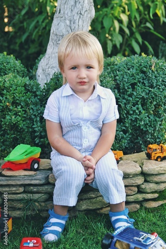 Portrait of little caucasian boy in casual clothes in home garden