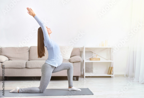 Young pregnant girl doing yoga at home