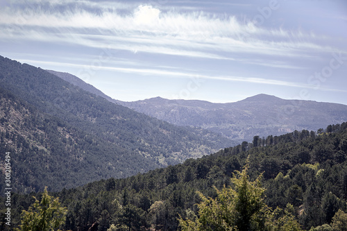 Panoramic of some mountains under a cloudy blue sky © luismicss