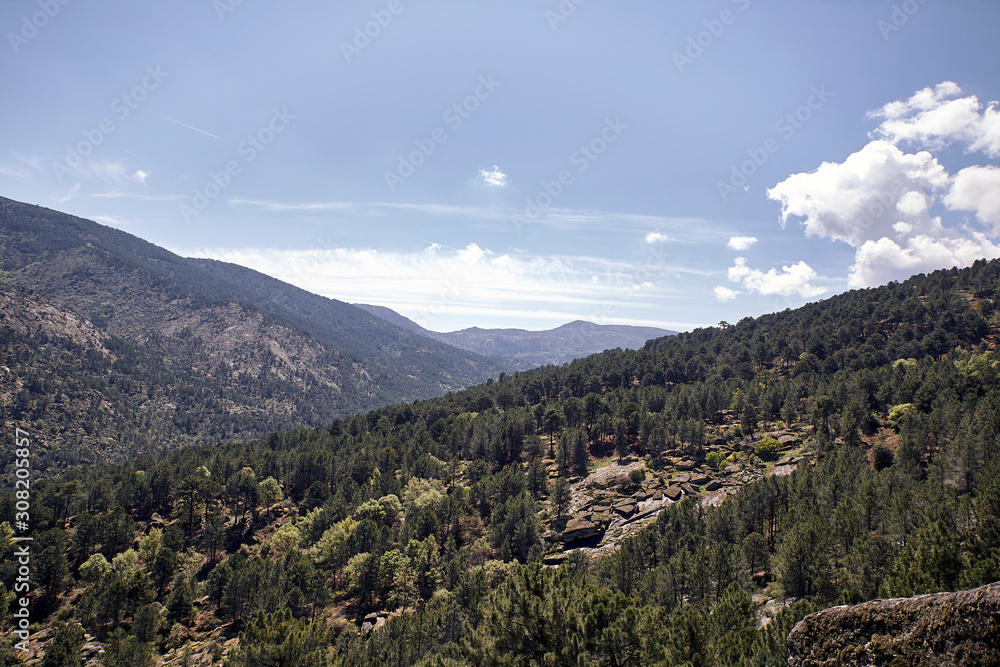 Panoramic of some mountains under a cloudy blue sky