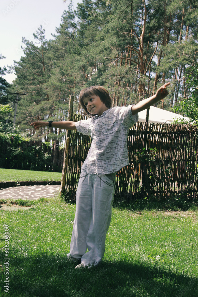 Portrait of little caucasian boy dancing in home garden