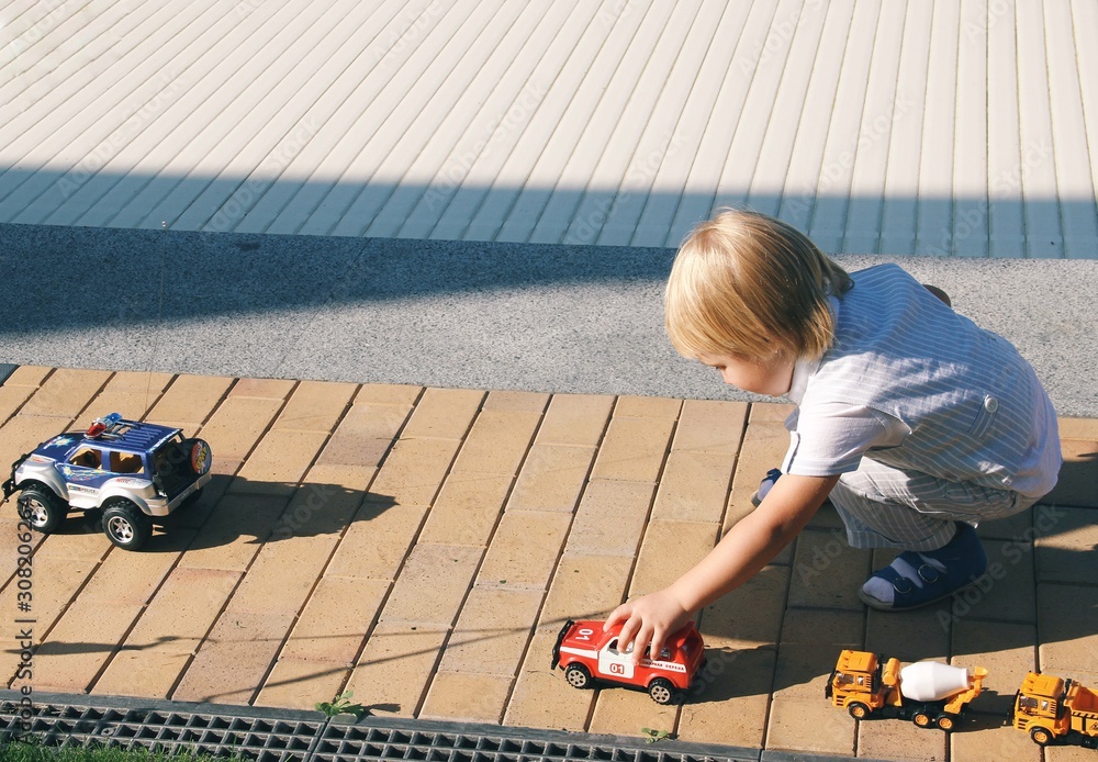 Portrait of little caucasian boy playing with toys on the street