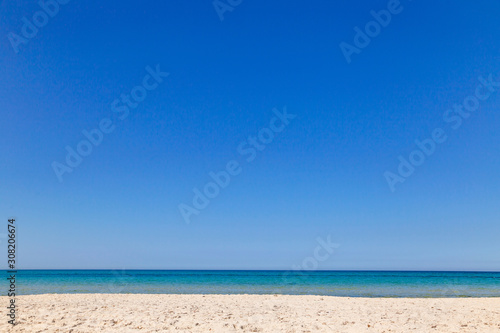 Beautiful peaceful sea water splashing at sandy seashore. Clear blue sky over sea water. Tunisia landscape. Horizontal color photography.