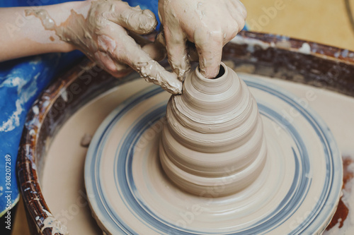 Woman hands on pottery wheel. Craftsman artist shapes pot photo