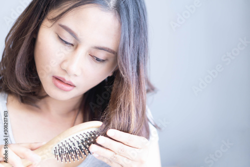 Woman hand holding comb with serious hair loss problem for health care shampoo and beauty product concept, selective focus