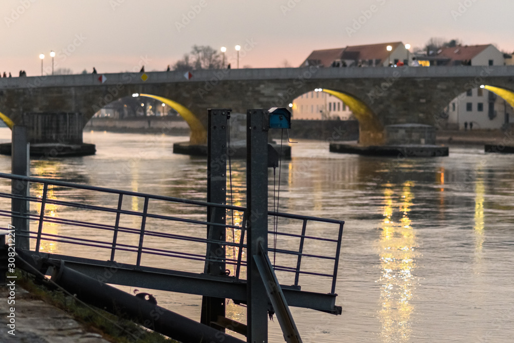Anleger und steinerne Brücke in Regensburg im Abendlicht.,