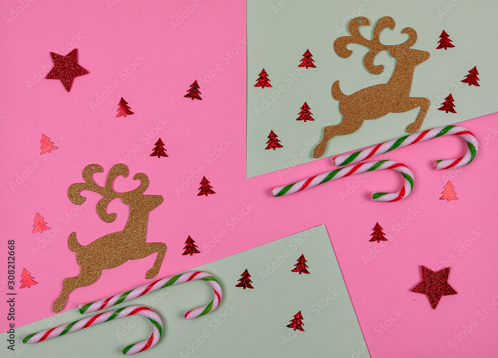 Christmas composition. Candy, Christmas deers and decorations toys on pink and green background. Christmas, winter, new year concept. Flat lay, top view